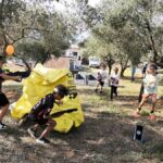 Groupe d’enfants jouant au Laser Game à Lunel, certains cachés derrière un obstacle artisanal jaune fait de palette et bâche, d’autres courant vers l’action.