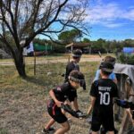 Groupe d’enfants jouant au Laser Game à Lunel, équipés de bandeaux et fusils laser, rassemblés près d’un but de football.